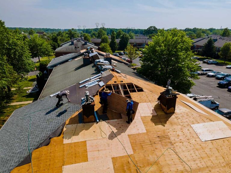 Roof eaves with open soffit vents, fascia, drip edge, and gutters beneath a shingled roof.