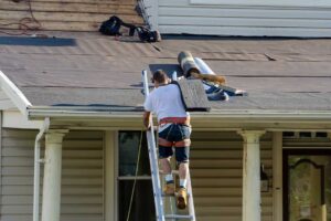 Roofing workers install shingles above a clean, insulated attic with visible ventilation channels.